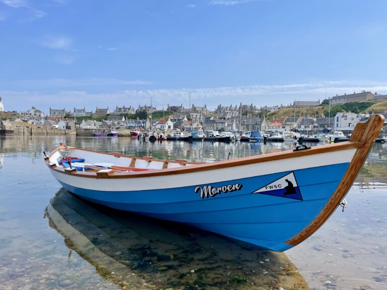 St Ayle's skiff Morven in the water at Findochty harbour on a clear, sunny day.